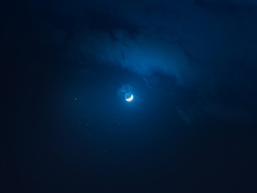 A wide view of a star-filled night sky with visible planets and glowing celestial light